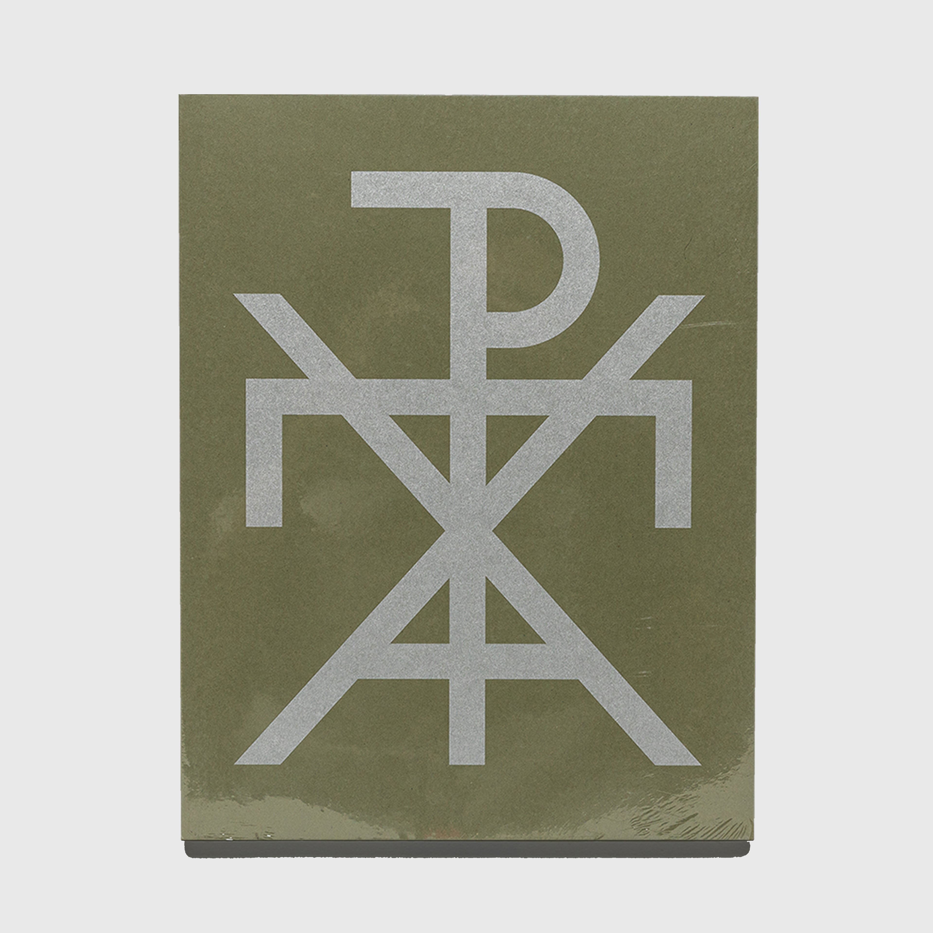 Green book with a silver logo on a white background. Gosha Rubchinskiy GR Uniforma photography book.