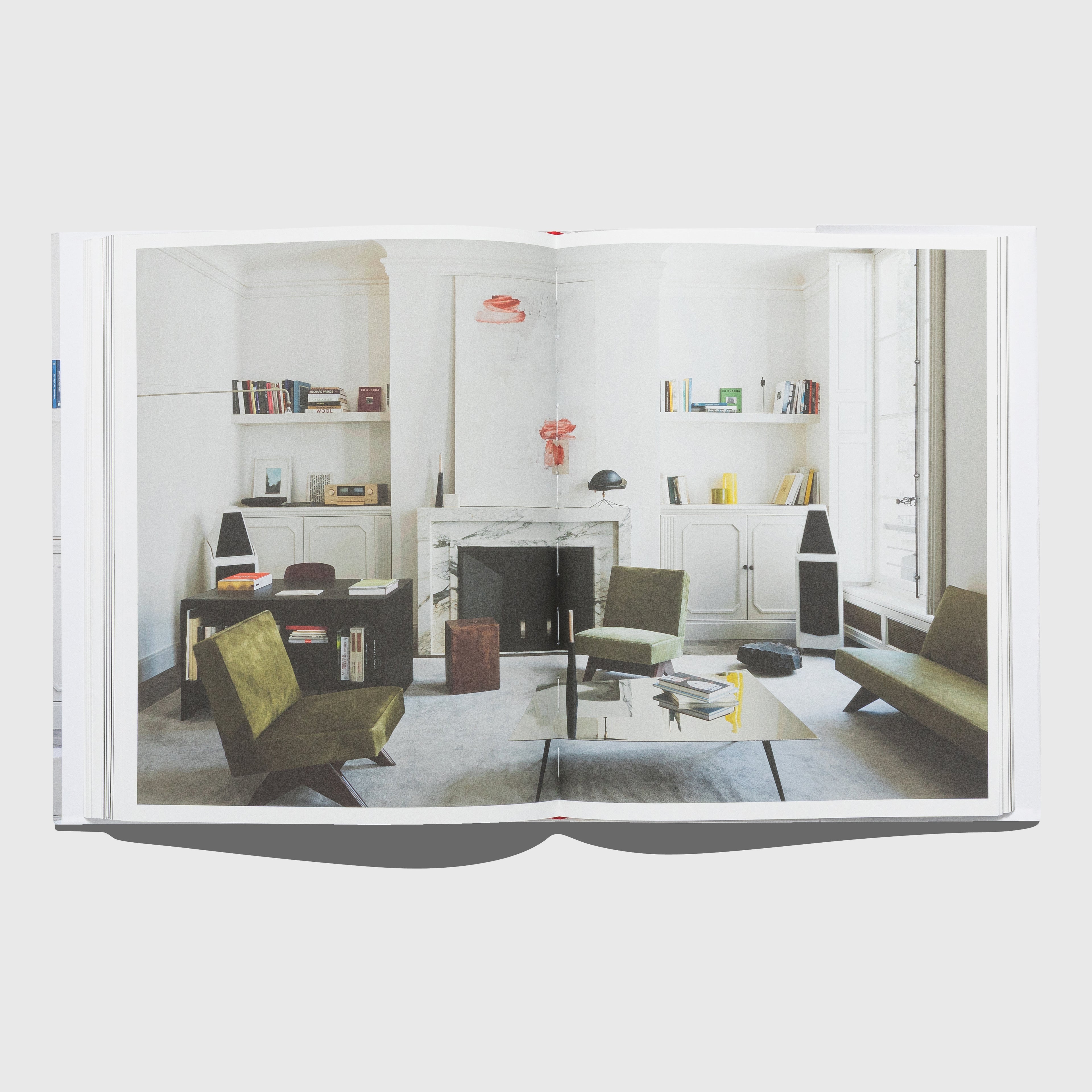 Open book showing a modern living room interior design. Pierre Jeanneret chairs. Interior by Joseph Dirand. Published by Rizzoli.