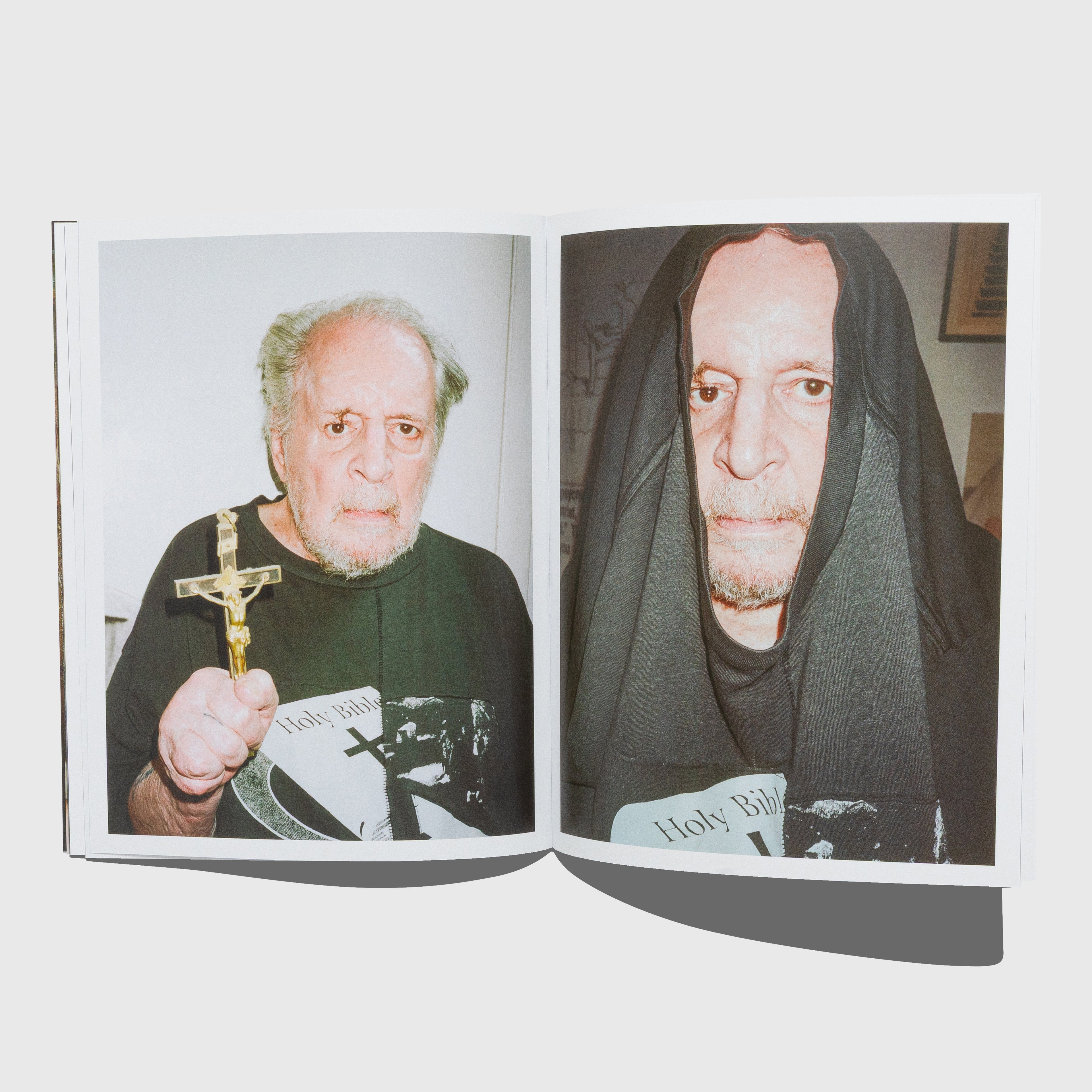Open book showing two pages with images of a man holding a cross and another wearing a black hood. Larry Clark photographed by Terry Richardson for Enfants Riches Déprimés. Rifleman book.