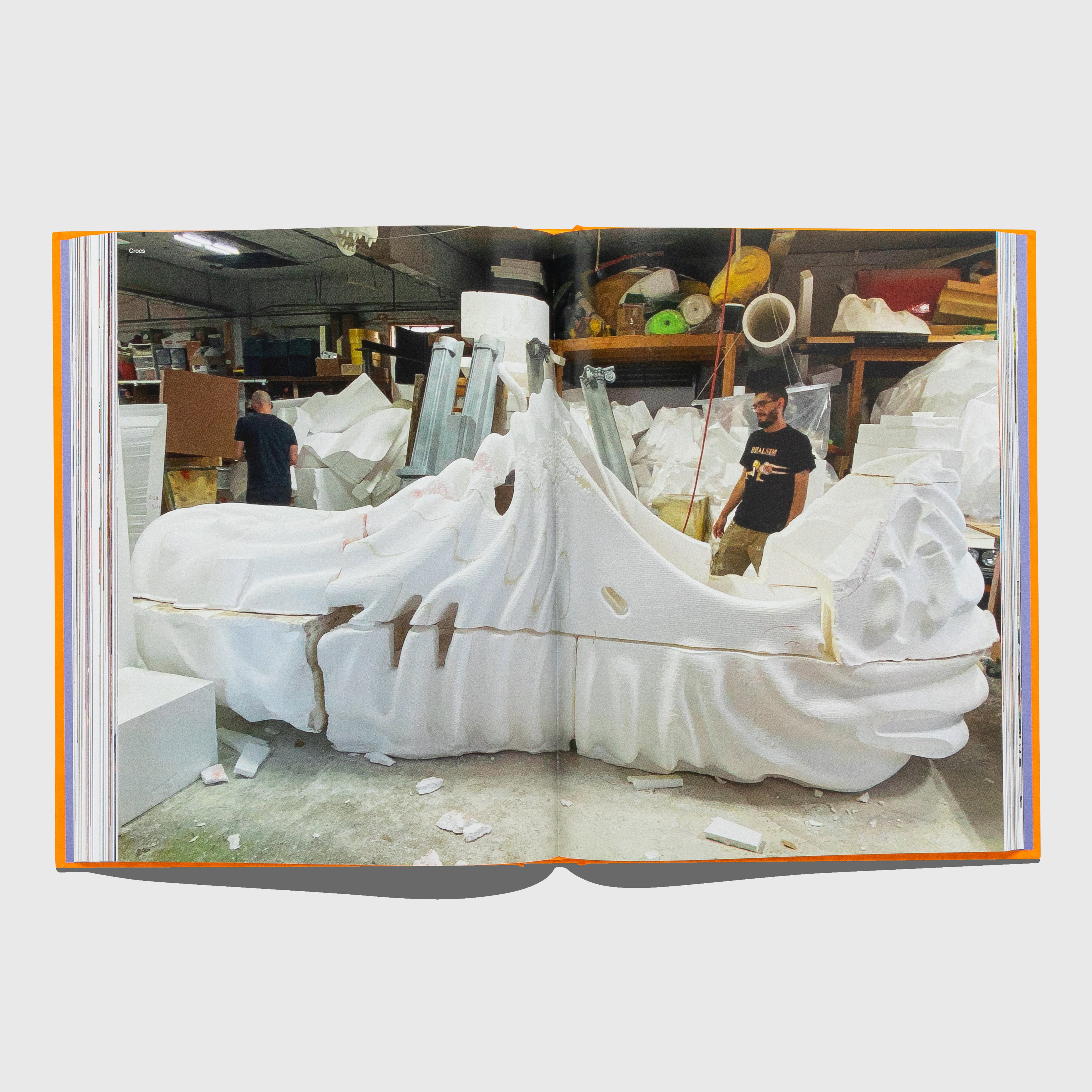 Open book showing a photograph of a large white sculpture in a workshop with people around. I MAKE SHOES book by Salehe Bembury. Published by Rizzoli. 