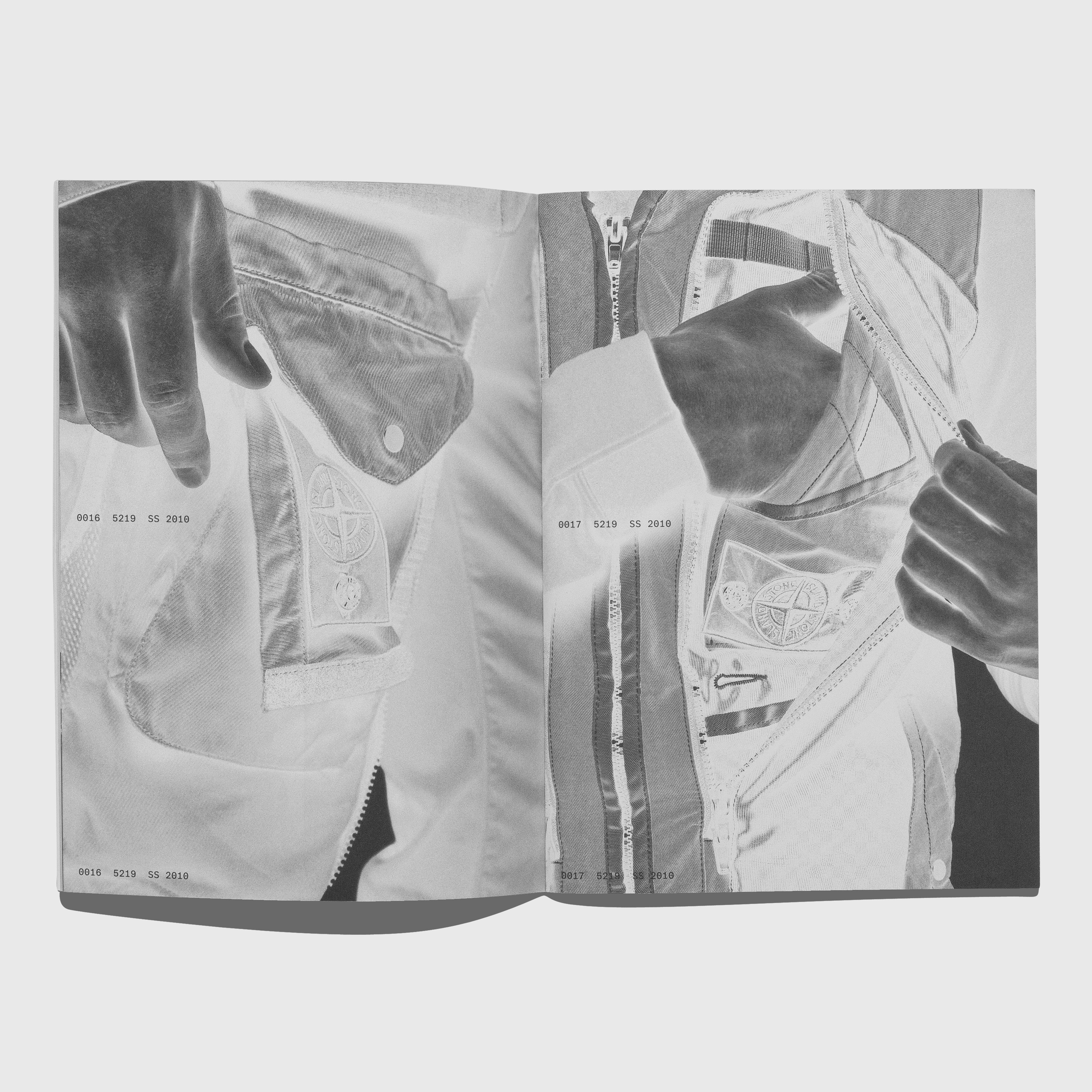 Open book showing black and white images of a jacket with zippers and buttons. Stone Island Shadow Project 2008-2020 by ACRONYM GMBH.
